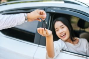 Wanita menerima kunci mobil dari sopir sebagai simbol proses rental mobil dengan sopir di Jakarta